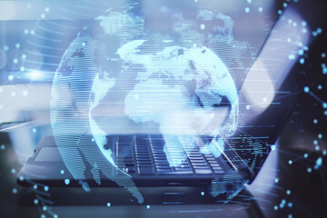 Poster - Close up of laptop with abstract globe interface on blurry desktop background. International communication and business concept. Double exposure.