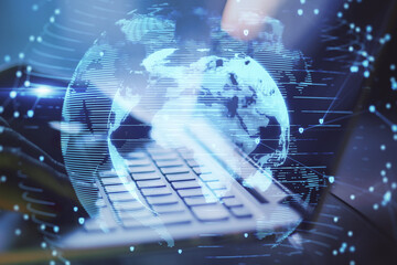 Poster - Close up of hands using laptop with abstract globe interface on blurry desktop background. International communication and business concept. Double exposure.