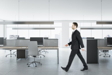 Poster - Businessman in suit walking in bright coworking meeting room interior with daylight, furniture and equipment. Design and ceo worker concept.
