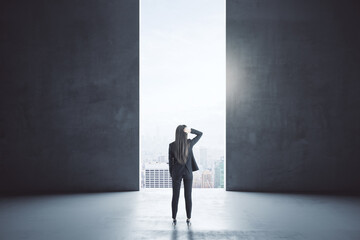 Wall Mural - Back view of young businesswoman looking at city though opening in concrete wall interior with mock up place. Success and vision concept.