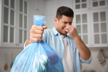 Wall Mural - Man holding full garbage bag at home, focus on hand