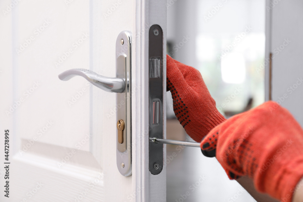 Handyman with screwdriver repairing door lock indoors, closeup - obrazy, fototapety, plakaty 