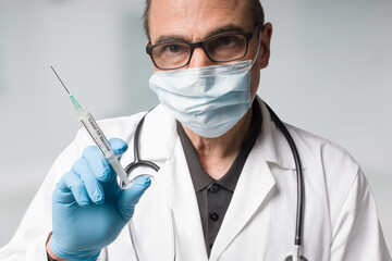 Wall Mural - doctor with medical face mask and medical gloves presenting a syringe pulled up with a coronavirus vaccine