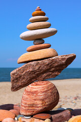 Wall Mural - Rock zen pyramid of colorful pebbles on a background of blue sky