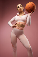 Wall Mural - Gorgeous young woman with basketball ball standing in studio