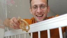 Young Happy Caucasian Father Looking At His Baby In Crib Shaking With Toy And Smiling. Bottom View From Child Eyes