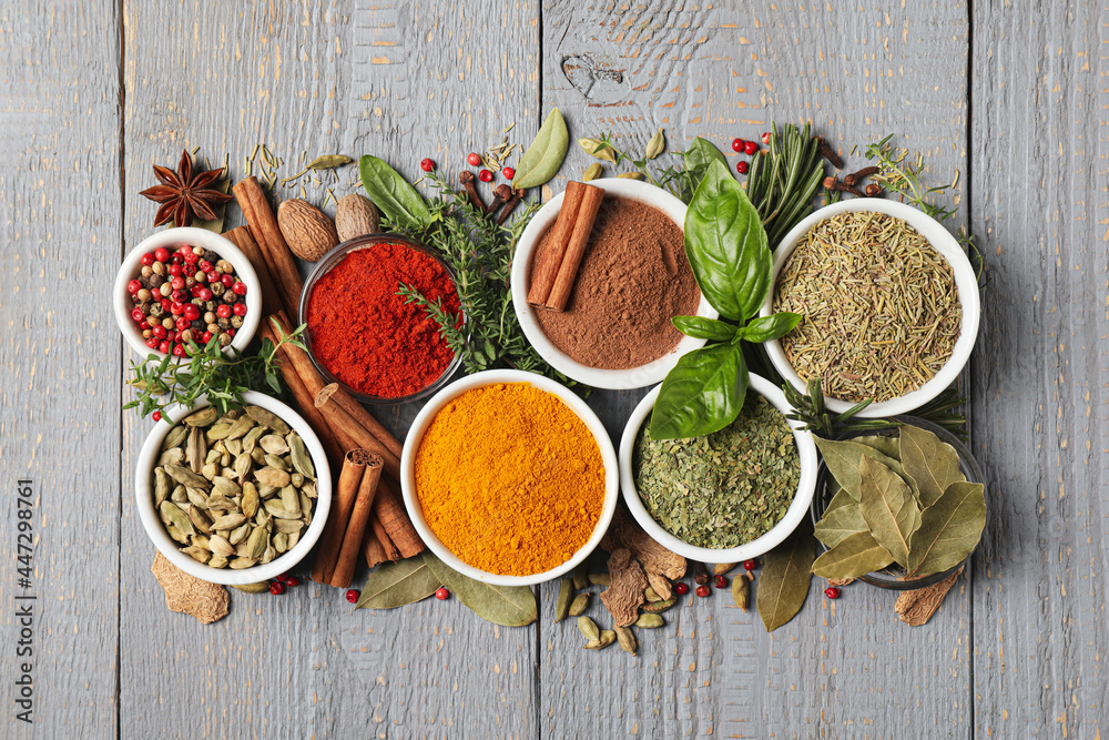 Different natural spices and herbs on grey wooden table, flat lay - obrazy, fototapety, plakaty 