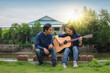 © Suriyo - Family couple playing guitar in garden at home