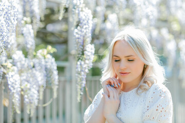 Portrait of a young beautiful woman in a blooming garden. Spring. Wisteria.