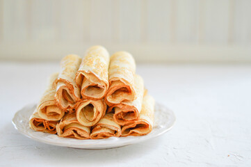 Traditional Russian Crepes Blini stacked in a white plate on light background. Maslenitsa traditional Russian festival meal. Russian food, russian kitchen