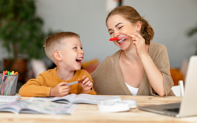 funny mother and child son playing and doing homework writing and reading