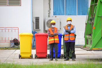 garbage collector Two garbagemen working together on emptying dustbins for trash removal with truck loading waste and trash bin.