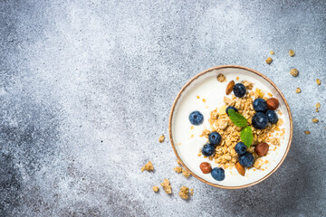 Wall Mural - Yogurt with granola and fresh berries at stone table. Top view with copy space.