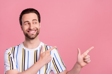 Poster - Photo of young happy cheerful young man point finger empty space smile isolated on pastel pink color background