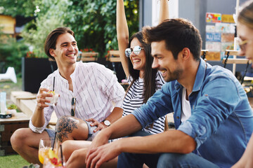 Group of young people drinking cocktails and have fun at a summer bar during the day