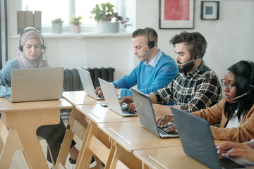 Wall Mural - Young intercultural customer support representatives working in front of laptops in office