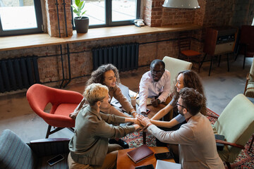 Aufkleber - Several multiracial colleagues making pile of hands over workplace