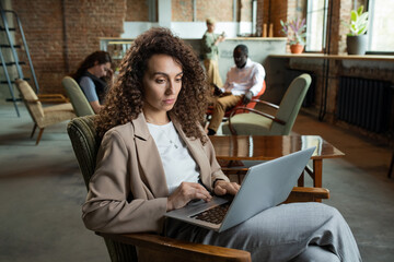 Aufkleber - Young businesswoman using laptop while sitting in armchair in office