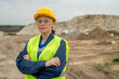Serious female construction worker crossing arms by chest against quarry