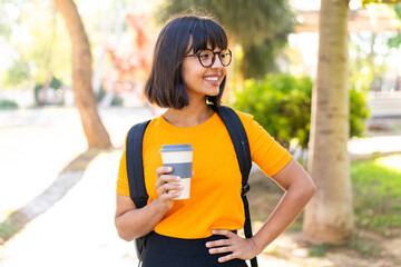 Wall Mural - Young student woman in a park holding a take away coffee