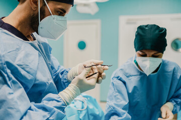 Wall Mural - Medical doctors preparing surgical equipment for operation inside private clinic - Focus on male doctor face