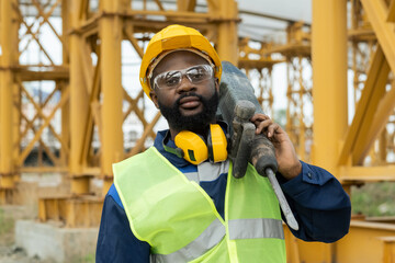 Poster - Portrait of African construction worker in work helmet looking at camera while working with drill on construction