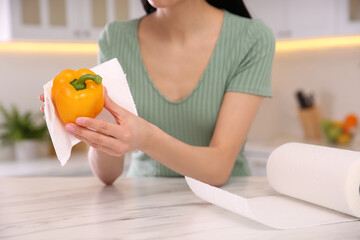 Sticker - Woman wiping bell pepper with paper towel in kitchen, closeup