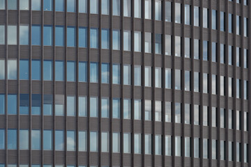 Wall Mural - Typical modern facade with rectangular grid frame structure and reflection of  blue sky on reflective glass of high rise office building. 