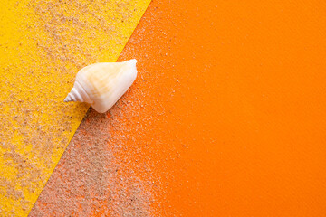 Conch seashell and sand on yellow and orange paper background. flat lay with free space. for vacation relax tourist tropical summer holidays background.