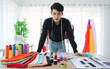 © Bangkok Click Studio - Smiling ethnic tailor with fabric samples in atelier