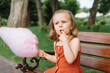 © kaloriya - Beautiful little girl eating pink cotton candy in the park.