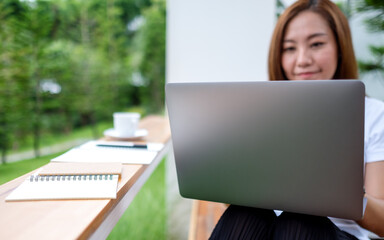 A young asian woman using and working on laptop computer in the outdoors