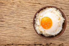 Streamed Rice With Runny Yolk Fried Egg And Sesame On Top On Rustic Natural Wood Texture Background With Copy Space For Text, Top View