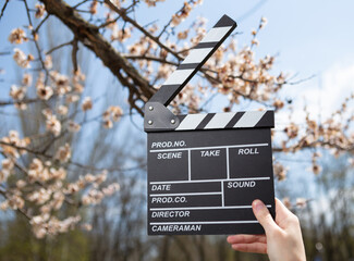 Wall Mural - Hand holds movie board on background of blossoming tree