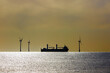 Clean energy. Heavy transport ship sihouetted between offshore wind turbines