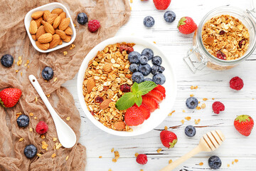 Poster - Tasty granola with fresh berries and almonds on white wooden background