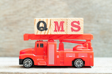 Canvas Print - Fire ladder truck hold letter block in word QMS (abbreviation of quality management system) on wood background