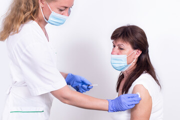 Wall Mural - Female doctor or nurse giving shot or vaccine to patient's shoulder. Vaccination and prevention against flu, virus pandemic, coronavirus. Mandatory vaccination of elderly people from the risk group.