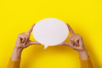 Talk bubble speech icon in hands over yellow background, layout for your text over white round space