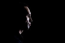Portrait Of A Caucasian Man In A Shirt In Profile On A Dark Background