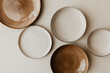 © Moodlia - Five different size plate on beige background. Textured grainy pattern on the plates. Flat lay, top view. Brown and natural color plates.