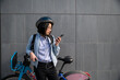 © Cavan Images - Young person looking at cell phone with urban bike rental