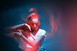 Mixed race young modern girl dancing in colourful neon light. Long exposure. Stylish female moving to rap rhythm