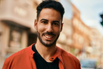 Young hispanic man smiling happy standing at the city.