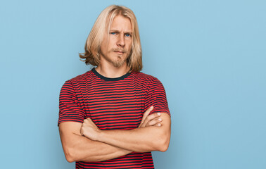 Canvas Print - Caucasian man with blond long hair wearing casual striped t shirt skeptic and nervous, disapproving expression on face with crossed arms. negative person.