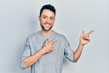 Poster - Young hispanic man pointing with fingers to the side smiling with a happy and cool smile on face. showing teeth.