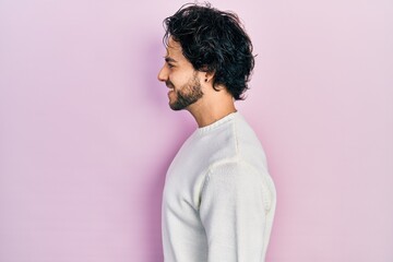 Poster - Handsome hispanic man wearing casual white sweater looking to side, relax profile pose with natural face and confident smile.