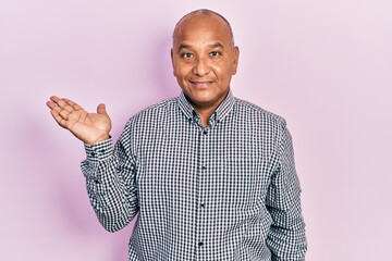 Wall Mural - Middle age latin man wearing casual clothes smiling cheerful presenting and pointing with palm of hand looking at the camera.