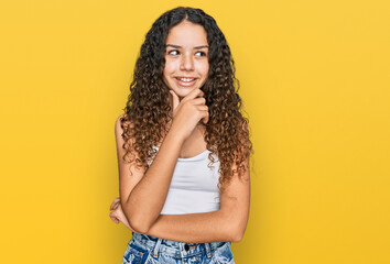 Wall Mural - Teenager hispanic girl wearing casual clothes with hand on chin thinking about question, pensive expression. smiling with thoughtful face. doubt concept.