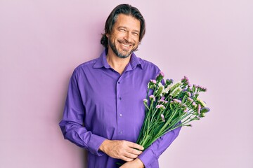 Canvas Print - Middle age handsome man holding flowers looking positive and happy standing and smiling with a confident smile showing teeth